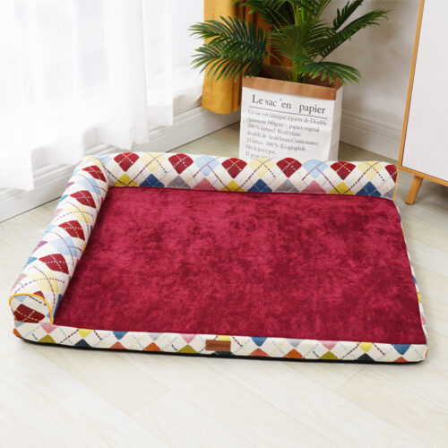 Cama esquinera de diseño con cuadros de colores y terciopelo rojo para perros con un perro encima