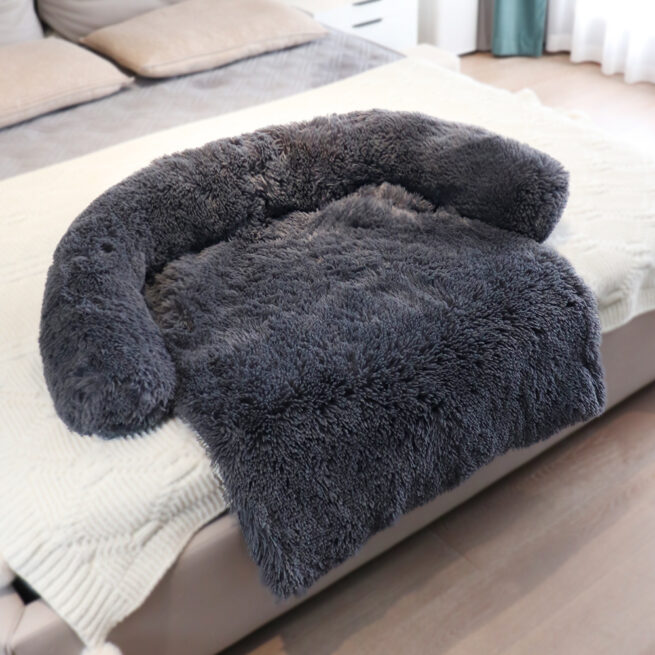 Cama para perros en el sofá suave color gris oscuro encima de una cama de humanos